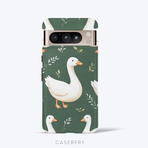 May include: A phone case featuring a repeating pattern of white geese with orange beaks and feet, set against a dark green background with sprigs of leaves. The case has a camera cutout and the brand name "CASEBERY" is printed at the bottom.