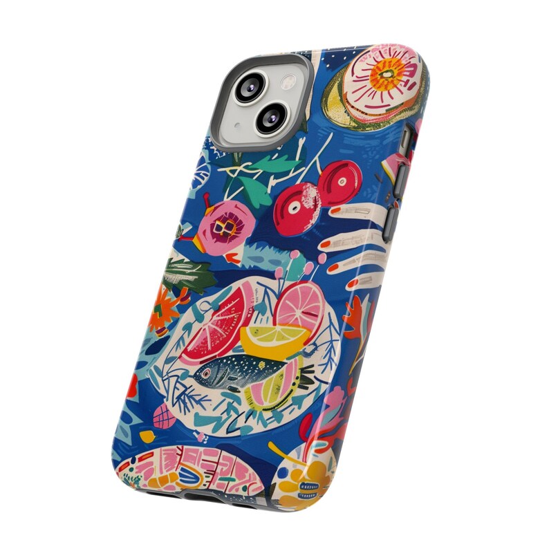 May include: A blue iPhone case with a colorful, artistic design. The case features a vibrant illustration of food, including fish, citrus fruits, and cherries, with floral and hand-drawn elements. The case has a glossy finish and a camera cutout.
