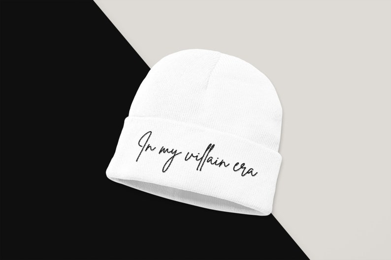 May include: White beanie with the text "In my villain era" in black cursive script.