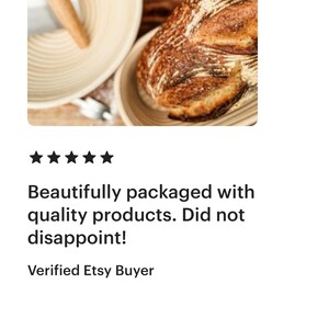 May include: A close-up of a sourdough bread loaf in a round, woven bread basket. The bread has a dark brown crust and a light brown interior. The basket is made of natural, light brown wicker. The image also includes a wooden dough scraper.