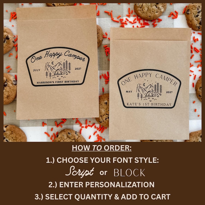 May include: Two rectangular brown paper bags featuring a black ink stamp design of a mountain landscape with a tent, trees, and the text One Happy Camper. One bag reads July 2027 Harrison's First Birthday, the other May 2027 Kate's 1st Birthday.