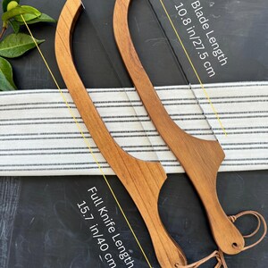 May include: Two wooden cake knives with a curved design. The blade length is 10.8 inches (27.5 cm), and the full knife length is 15.7 inches (40 cm). Each knife has a leather cord attached to the handle.