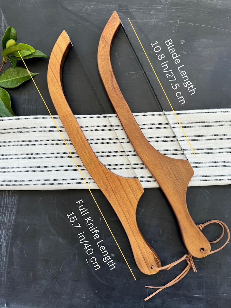 May include: Two wooden cake knives with a curved design. The blade length is 10.8 inches (27.5 cm), and the full knife length is 15.7 inches (40 cm). Each knife has a leather cord attached to the handle.