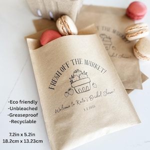 May include: Brown paper bags with the text "FRESH OFF THE MARKET!" and a strawberry basket graphic. The bags, measuring 7.2in x 5.2in, are filled with macarons. Text on the bag reads "Welcome to Kate's Bridal Shower! 8.2.2025".