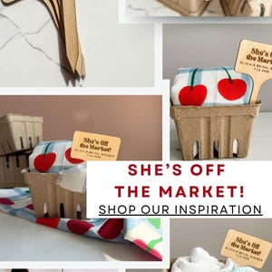May include: A collage of images featuring wooden signs that read "She's Off the Market!" for Olivia's bridal shower. The signs are paired with cherries and decorative baskets. The text "Shop Our Inspiration" is also visible.