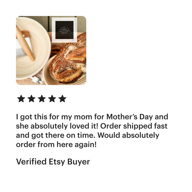 May include: A close-up of a round, woven bread proving basket with a loaf of sourdough bread inside. The basket is made of natural, light brown rattan and has a wooden dowel inside. The bread is golden brown and has a rustic, crusty exterior.