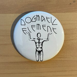 Op de afbeelding: Witte knop met zwarte tekst die "Dogmatic Element" zegt en een zwarte lijntekening van een persoon met uitgestrekte armen.