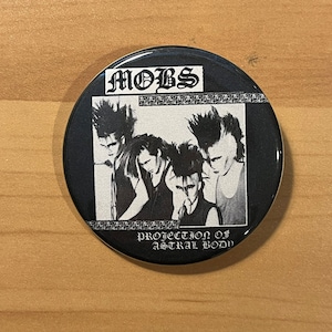 May include: Black and white button badge featuring a band called "MOBs" with the text "Protection of Astral Body".