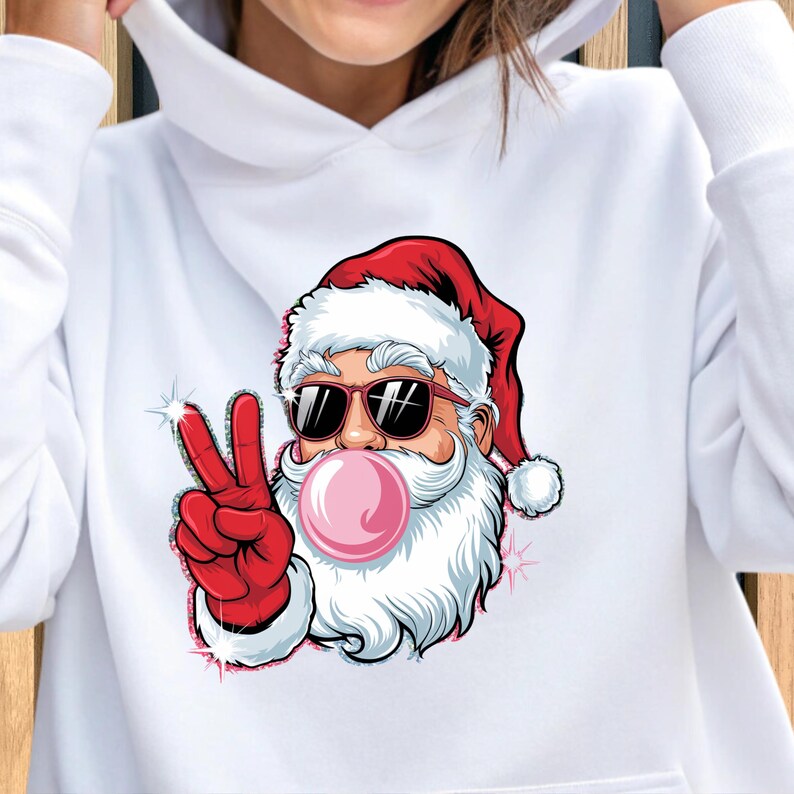 May include: White hoodie with a graphic of Santa Claus wearing sunglasses and blowing a pink bubble. Santa is giving the peace sign with his right hand.
