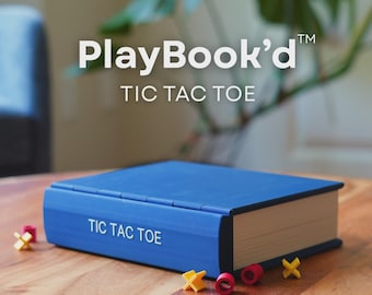 May include: A blue book-shaped game box with the text PlayBook'd TIC TAC TOE printed on the cover and spine. The game includes small yellow X-shaped pieces and red O-shaped pieces scattered around the base of the blue rectangular box.