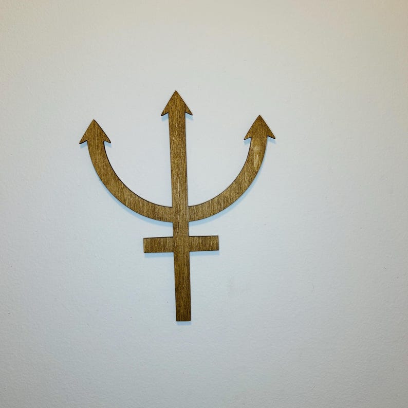 May include: A brown wooden wall decoration shaped like the astrological symbol for Neptune, featuring a central vertical shaft with a crossbar near the bottom and two curved arms extending upward, each ending in a pointed arrow tip.