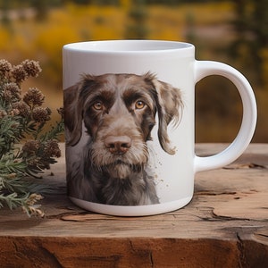 May include: White ceramic coffee mug with a brown and black dog illustration. The dog has brown eyes and a serious expression. The mug has a white handle.