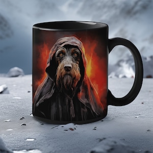 May include: Black ceramic mug featuring a graphic of a dog wearing a black hooded cloak. The dog has brown fur and a serious expression. The background is a fiery orange and yellow.