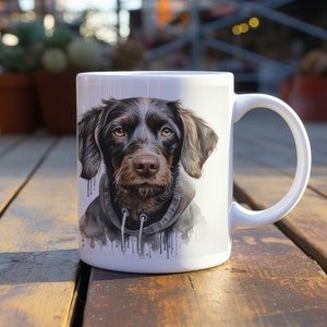 Puede incluir: Taza de cerámica blanca con una ilustración en acuarela de un perro marrón con una sudadera gris. El perro tiene ojos marrones y una expresión concentrada. La taza tiene un asa grande.