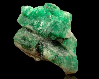 May include: A large, green emerald crystal with a rough, natural texture. The crystal is a deep green color and has a slightly cloudy appearance.