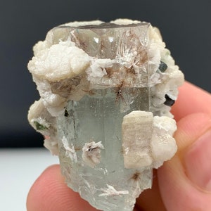May include: A light blue aquamarine crystal with white and brown inclusions. The crystal is surrounded by white and brown matrix.