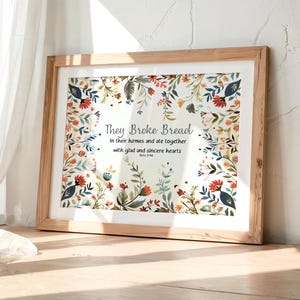Peut inclure: Une impression d'art encadrée sur fond crème clair avec une bordure florale colorée composée de feuilles et de fleurs rouges, bleues et vertes. Le texte indique : They Broke Bread In their homes and ate together with glad and sincere hearts Acts 2:46.