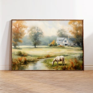Peut inclure: Peinture de paysage encadrée représentant une scène de campagne sereine. Un cheval blanc broute près d'un ruisseau dans un champ herbeux, avec une maison blanche en arrière-plan. L'œuvre présente des couleurs chaudes, avec des arbres et un feuillage aux tons orangés et verts.
