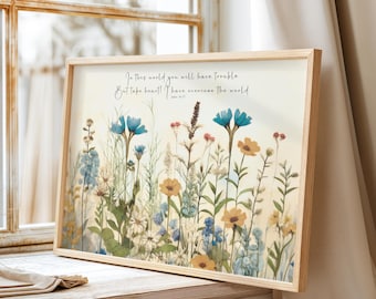 Peut inclure: Une impression encadrée avec une illustration aquarelle d'un champ de fleurs sauvages dans des tons de bleu, jaune et vert. L'impression présente la citation "Dans ce monde, vous aurez des épreuves, mais prenez courage ! J'ai vaincu le monde." Jean 16:33.