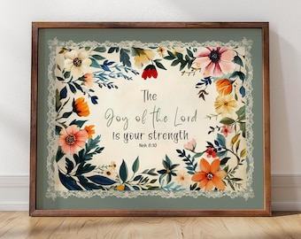 May include: A framed print with a floral design and the quote "The Joy of the Lord is your strength" with the scripture reference Neh 8:10.
