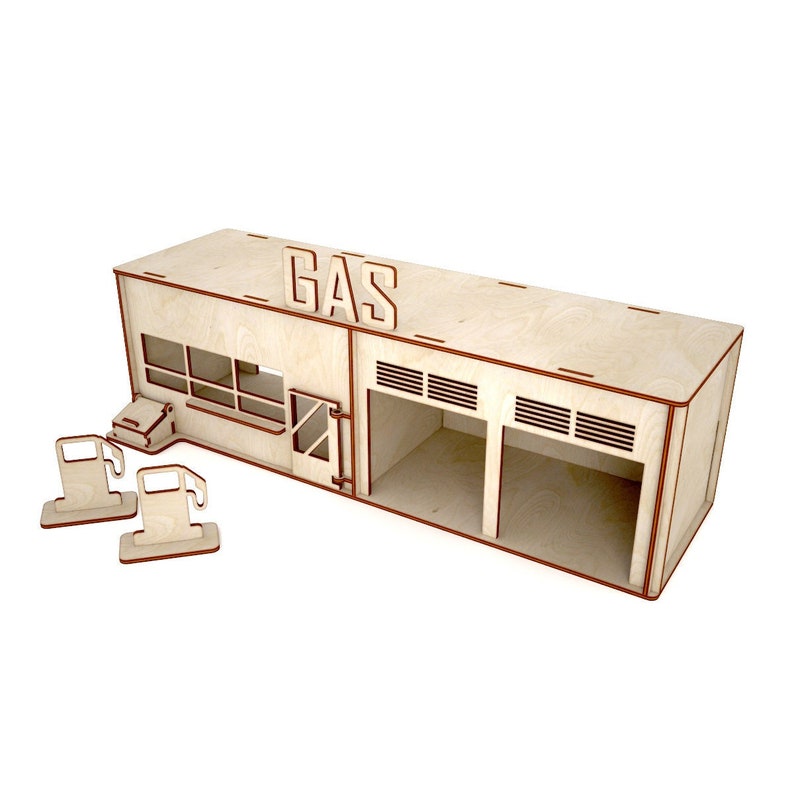May include: A wooden model of a gas station with two garage doors, a sign that says "GAS", and two gas pumps. The model is made of light brown wood and has a red trim.