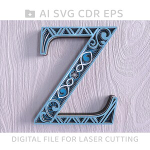 Peut inclure: Une découpe laser complexe de la lettre Z, en bleu et blanc, avec un motif géométrique. La lettre est sur un fond en bois blanc. Fichier numérique pour découpe laser.