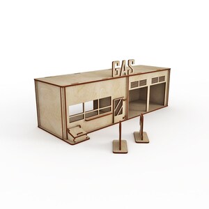 May include: A wooden model of a gas station with a sign that reads "GAS" on the roof. The model has a garage door, a window, and a door. There are two gas pumps in front of the station.