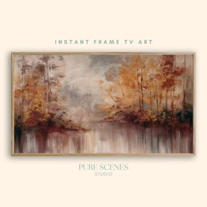 May include: A rectangular landscape painting in a wooden frame featuring an autumn forest scene with trees in shades of orange, brown, and gold reflected in a calm body of water. The text INSTANT FRAME TV ART and PURE SCENES STUDIO is visible.