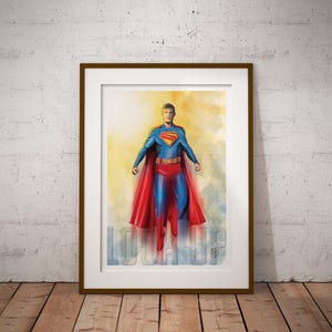 May include: Framed artwork featuring a watercolor illustration of Superman in his iconic costume. The image shows Superman in a dynamic pose with a red cape, blue suit, and the Superman logo. The word "LOOK UP" is written in the lower part of the image.
