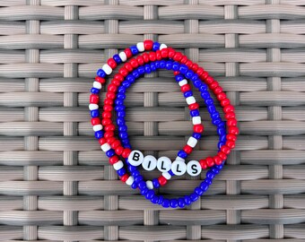 May include: Three beaded bracelets in red, white, and blue colors, spelling out "BILLS" in white letters.