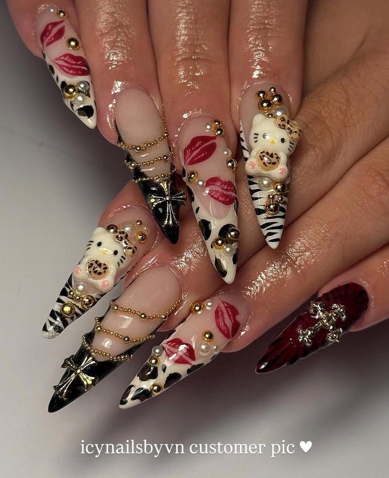 Puede incluir: Una manicura con u&ntilde;as acr&iacute;licas largas y puntiagudas con varios dise&ntilde;os. Algunas u&ntilde;as presentan un dise&ntilde;o de Hello Kitty, otras labios rojos y otras un estampado de vaca en blanco y negro. Tambi&eacute;n hay detalles dorados y perlados.