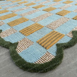 Tapete de lã tufado à mão com borda ondulada, azul e verde.
