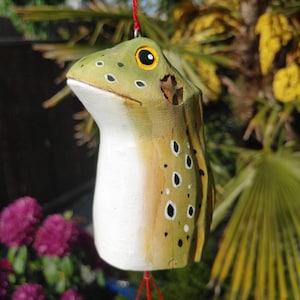Peut inclure: Ornement en bois en forme de grenouille, peint en vert et blanc. La grenouille a des taches noires et un œil jaune, suspendue à un fil rouge. Un objet décoratif charmant et fantaisiste.