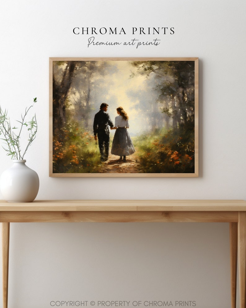 以下が含まれることがあります： 森の中の小道を歩くカップルを描いた額入りのアートプリント。アートワークは、温かみのある色調と「CHROMA PRINTS Premium art prints」のテキストを備えた、柔らかく絵画的なスタイルです。