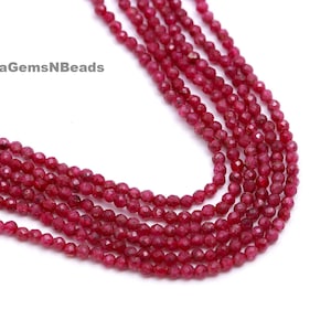 Op de afbeelding: Een streng rode robijn edelsteen kralen. De kralen zijn gefacetteerd en hebben een ronde vorm. De streng is ongeveer 40 cm lang.