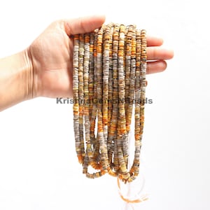 Pode incluir: Um fio de contas multicoloridas, com tons de marrom, laranja e branco. As contas são pequenas e redondas, e são enfiadas em um fio branco.