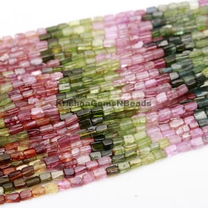 May include: A strand of multi-coloured tourmaline beads. The beads are faceted and have a rectangular shape. The colours of the beads are pink, green, and black.