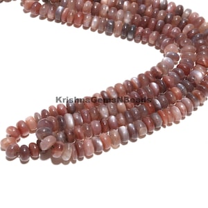 May include: A strand of sunstone beads in shades of pink and gray. The beads are round and have a smooth, polished finish. The beads are strung on a clear thread.