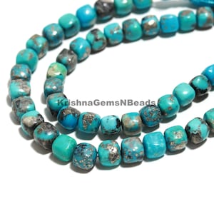 Puede incluir: Primer plano de cuentas cuadradas de color turquesa con patrones grises y plateados. Las cuentas están ensartadas, mostrando una textura de piedra natural. La imagen incluye el texto "KrishnaGemsNBeads".