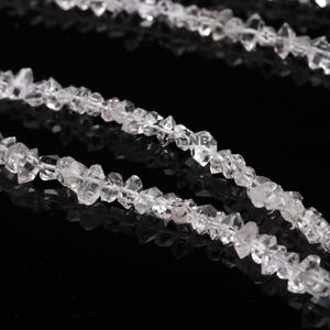 May include: A strand of clear, faceted, rough-cut crystal beads. The beads are irregular in shape and size, and they have a natural, unpolished look.