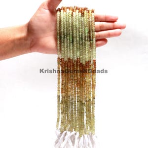 Pode incluir: Um fio de contas de pedras preciosas verdes e marrons. As contas são pequenas e redondas, e são enfiadas em um fio branco. O fio tem aproximadamente 46 cm de comprimento.