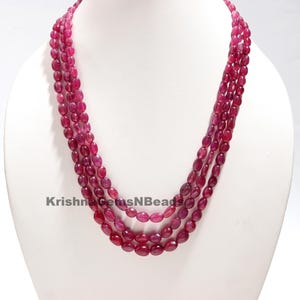 Op de afbeelding: Een meerrijige ketting gemaakt van ovale, roze robijn kralen. De ketting is gelaagd en heeft in totaal vier rijen.