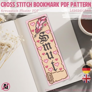 Pode incluir: Padrão PDF de marcador de ponto cruz com a palavra "Smut" em letras góticas pretas, rodeada por corações rosa e um desenho de pena. O marcador está em um livro, com texto em inglês e alemão.