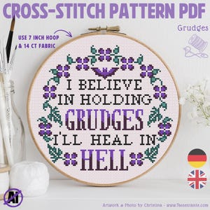 Könnte beinhalten: Ein Kreuzstichmuster-PDF in einem Holzrahmen. Das Design zeigt den Text "I BELIEVE IN HOLDING GRUDGES I'LL HEAL IN HELL" in Schwarz und Lila. Das Muster benötigt einen 17,78 cm Rahmen und 14-Count-Stoff.