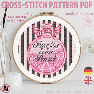 Könnte beinhalten: Ein Kreuzstichmuster-PDF in einem Holzrahmen. Das Design zeigt einen rosa Parfümflakon mit dem Text "Smells like Smut". Der Hintergrund hat schwarz-weiße Streifen. Das Muster benötigt einen 17.78 cm Stickrahmen.
