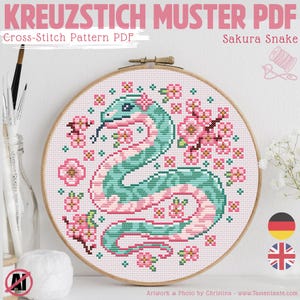 Könnte beinhalten: Ein Kreuzstichmuster mit einem Sakura-Schlangen-Design in einem Holzrahmen. Die Schlange ist türkis und rosa, umgeben von rosa Kirschblüten. Der Text "KREUZSTICH MUSTER PDF" und "Sakura Snake" sind sichtbar. Es ist ein PDF-Kreuzstichmuster.