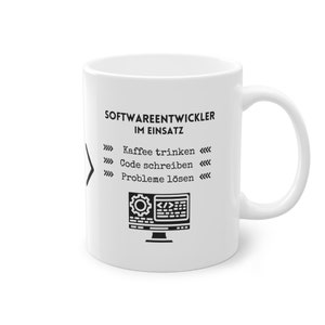 May include: White ceramic mug with a black design that says "Softwareentwickler im Einsatz" and includes a list of tasks: "Kaffee trinken", "Code schreiben", "Probleme lösen". The design also includes a black and white illustration of a computer monitor with a gear and code on the screen.