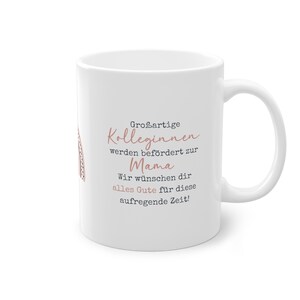 May include: White ceramic mug with a pink and gray design. The text on the mug reads "Großartige Kolleginnen werden befördert zur Mama Wir wünschen dir alles Gute für diese aufregende Zeit!"