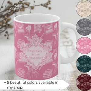 May include: A pink ceramic mug with a white design featuring a typewriter, books, and a heart with the text "High Lady of the Smut Court".