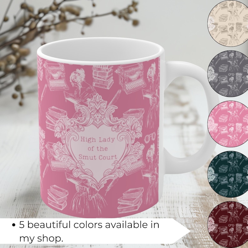May include: A pink ceramic mug with a white design featuring a typewriter, books, and a heart with the text "High Lady of the Smut Court".